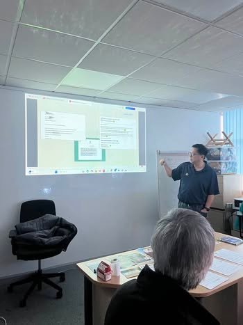 A trainer pointing to an email inbox on a projector screen during a digital skills session in Salford
