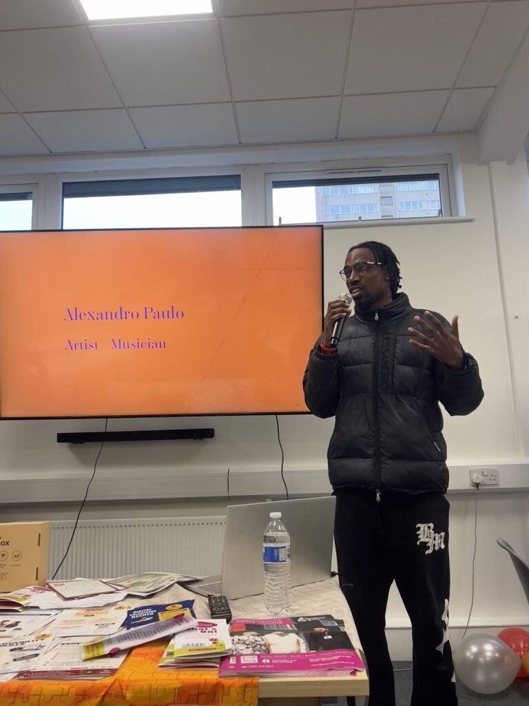 A speaker addressing the room in front of an orange screen