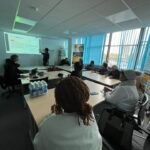 Learners at tables during a Salford Digital Café internet security session, with a trainer at the projector screen