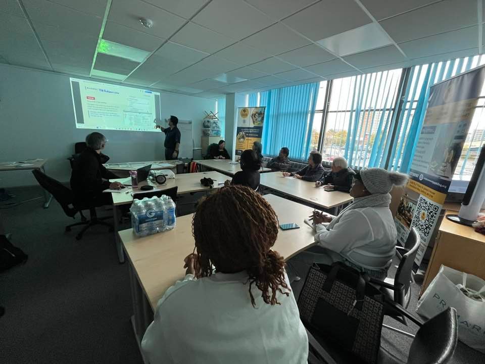 Learners at tables during a Salford Digital Café internet security session, with a trainer at the projector screen